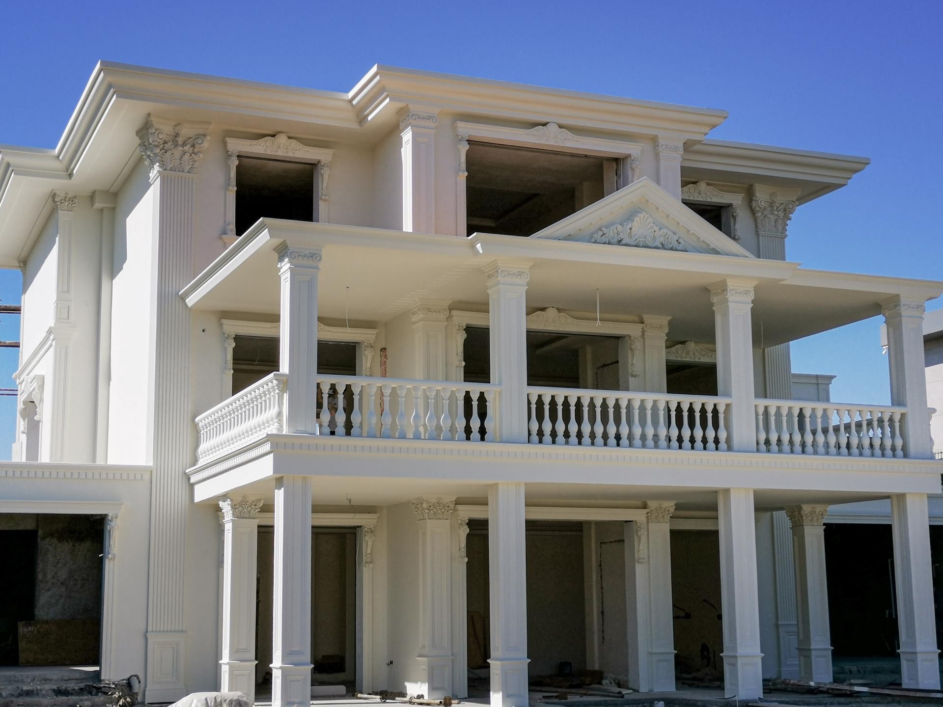 Beyaz renkli bir dış cephe üzerinde tasarlanmış poliüretan dekoratif pencere söveleri ve pilaster sütun kaplamaları.