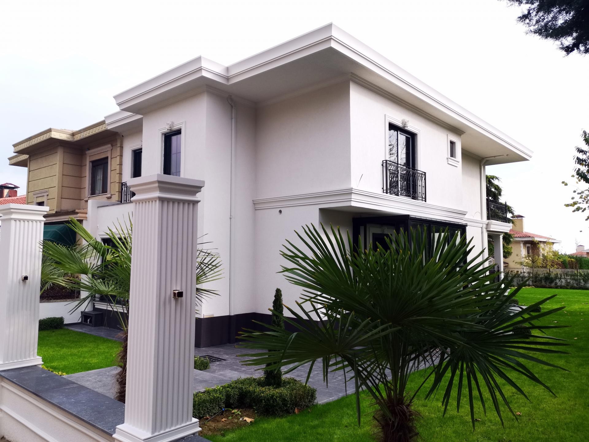 Beyaz dış cepheli ve antrasit zemin katlı müstakil evde, yivli pilaster sütunlar ile beyaz söve çerçevelerinin görünümü.