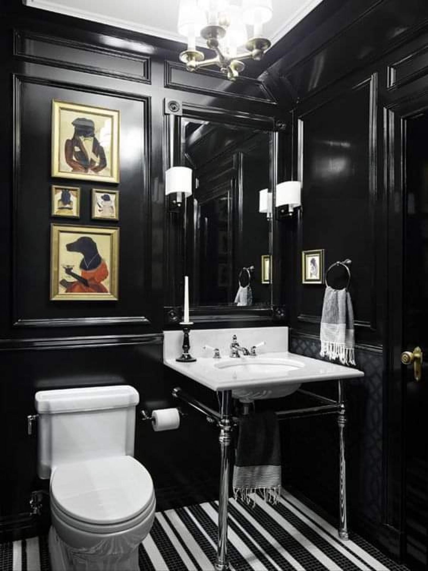Siyah parlak duvarda dikey çıta kasetleri, altın aplikler ve krom ayaklı beyaz banyo lavabosu.