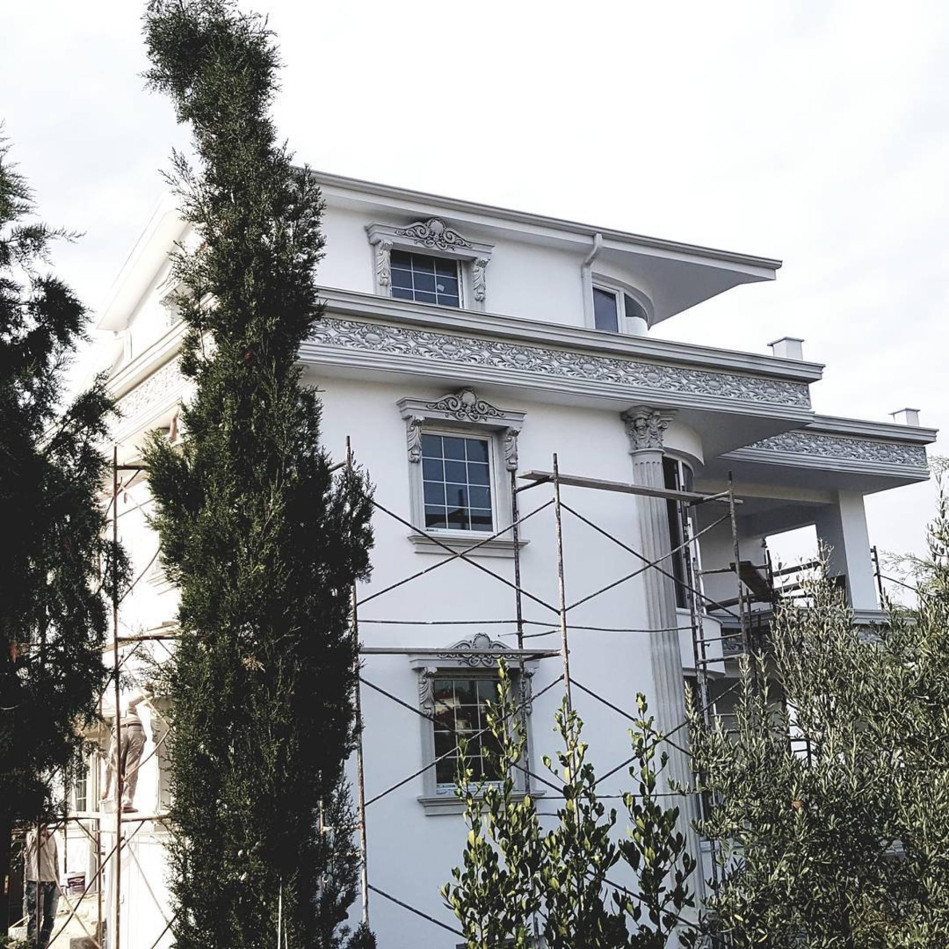 İskele kurulu müstakil bir villanın dış cephesinde montajı devam eden beyaz renkli poliüretan sütun, söve ve friz kaplamaları.