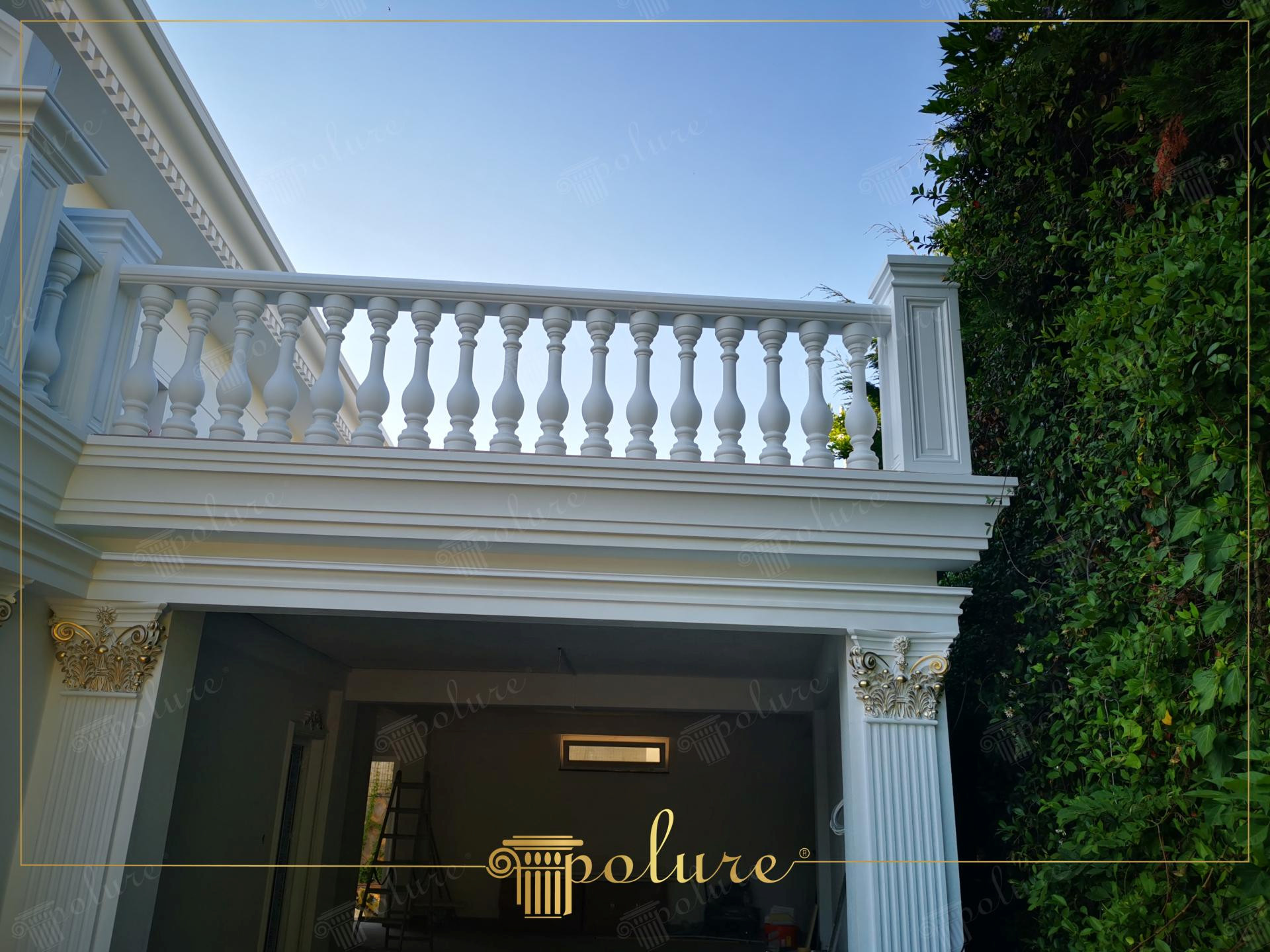 Altın sarısı boyalı başlıkları olan pilaster sütunlar, balkon korkulukları ve beyaz dış cephe söveleri.