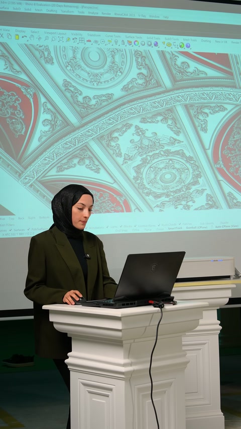 Sunucu, projeksiyondaki kavisli tavan planını dizüstü bilgisayardan anlatıyor