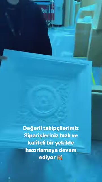 Görevli, kabartma desenli dikdörtgen paneli dik konumda tutuyor.