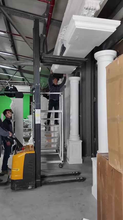 Görevli, sütunlarla çevrelenen giriş tacında üst montaja hazırlanıyor.