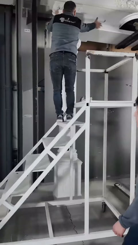 Merdivendeki çalışan, geniş tacın duvar tarafındaki kenarını ayarlıyor.