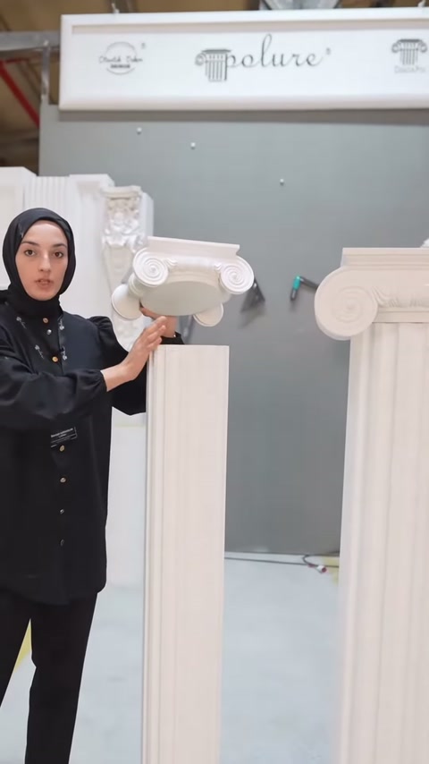 Sunucu ince sütunun volütlü başlığını eliyle tutarak ayrıntıları anlatıyor