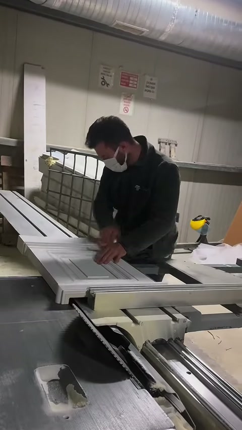 Usta, kabartmalı söve parçalarını makine hattı boyunca itiyor.