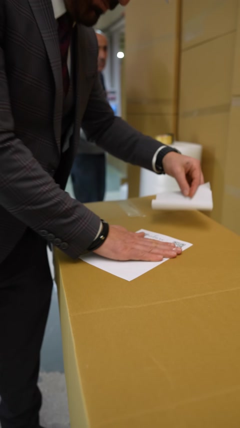 Paketlenen karton kutuya ürün etiketi elle yapıştırılıyor