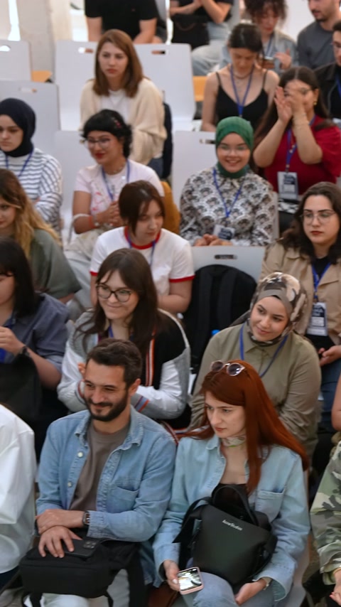 Amfi sıralarındaki öğrenciler uygulama bölümünü topluca izliyor