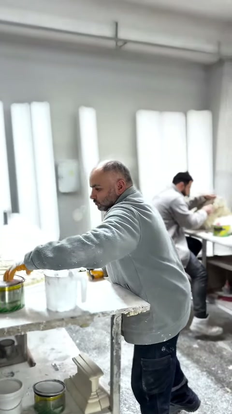 Üretim masasında çalışan usta, beyaz parçanın kenarlarını kontrol ediyor.