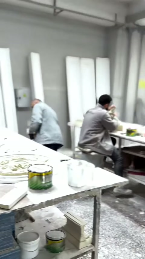 İki usta, yivli gövdelerin önündeki masada üretime devam ediyor.