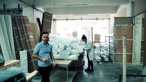 Usta, istiflenmiş süsleme parçalarının önünden çalışma alanına ilerliyor.