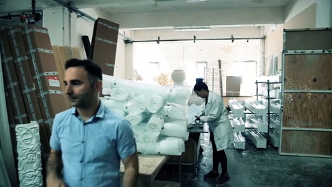 Çalışan ön plandan geçerken arkada beyaz konsollar sıralanıyor.