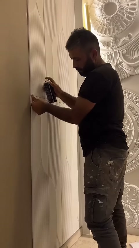 Usta duvar kaplamasının dikey ekini bastırarak yüzeyi kontrol ediyor.