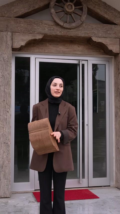 Sunucu elindeki sarılı kiriş numunesini giriş kapısı önünde tutuyor