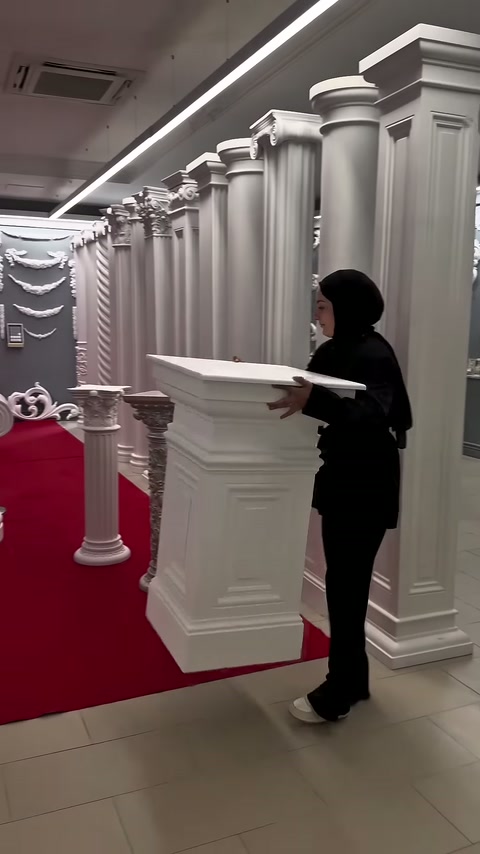 Tanıtıcı, kare gövdeli sehpanın tablasını iki eliyle hizalıyor.