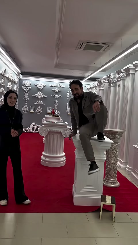 Erkek, tanıtıcı yanında dururken basamaktan sehpa tablasına çıkıyor.