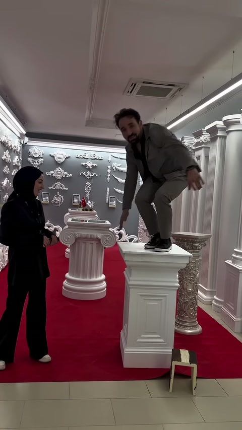 Erkek, showroomdaki kare sütun sehpanın tablası üzerinde ayakta duruyor.