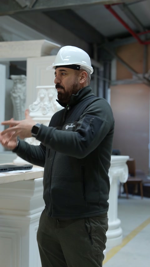 Usta dekoratif sütunların önünde iki eliyle genişlik işareti yapıyor