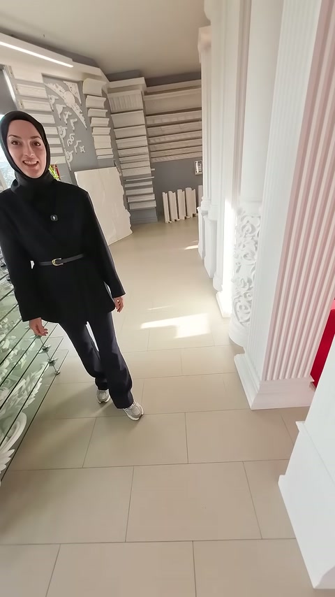 Sunucu, köşeli pilasterlerin önünde showroom sunumuna devam ediyor.