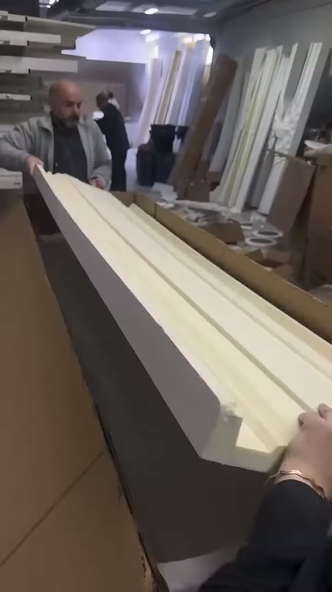 Oluklu açık renk profiller uzun karton kutuya yerleştiriliyor