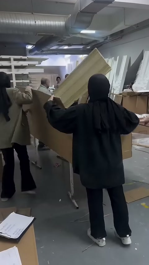 Karton kutunun uzun yan kapağı çalışanlar tarafından yukarı kaldırılıyor