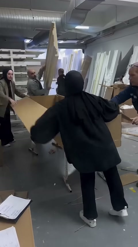 Paketleme ekibi kutu kapaklarını ürünlerin üzerinde bir araya getiriyor