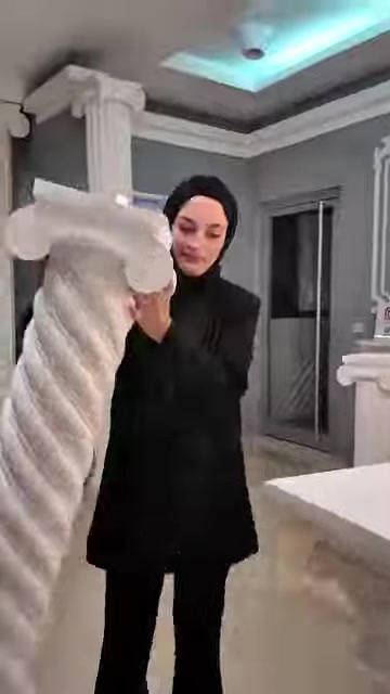 Sunucu, kıvrımlı gövdeli beyaz dekoratif sehpa modelini yakından inceliyor.