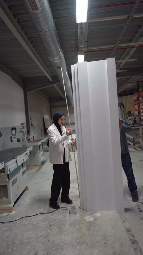 Dikey profiller atölyede sıralanırken sunucu kenar detayına dokunuyor.