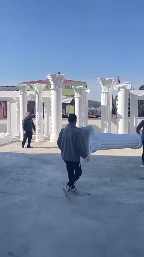 Çalışan, yatay tuttuğu beyaz sütun gövdesiyle teşhir sıralarına yaklaşıyor