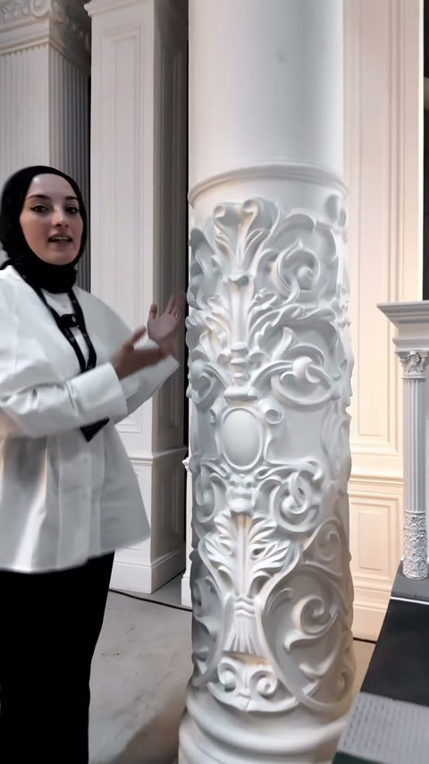 Sunucu showroomda kabartmalı alt bölüme sahip yüksek sütunu tanıtıyor.