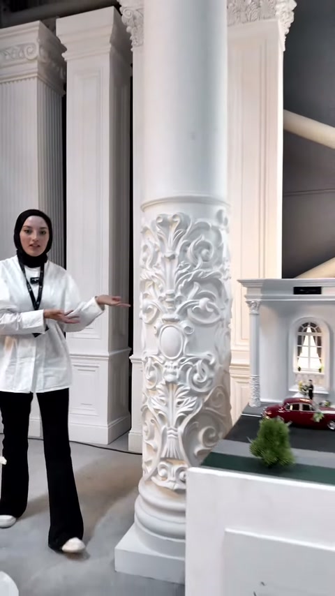 Sunucu yüksek dekoratif sütunun yanında durup yüzey ayrıntılarını anlatıyor.