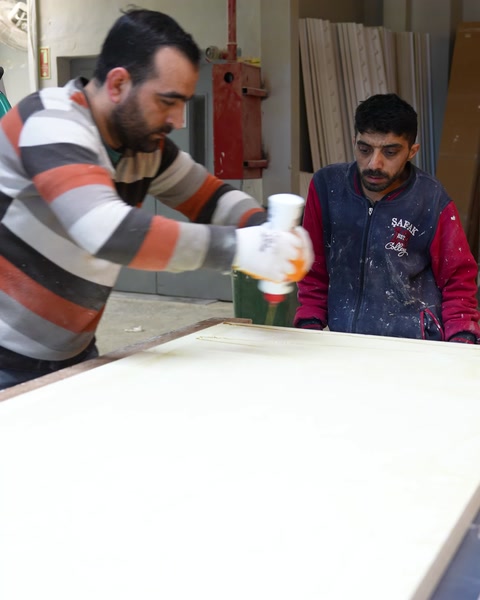 Kesilmiş masa panelinin yüzeyine montaj malzemesi düzenli şekilde uygulanıyor.