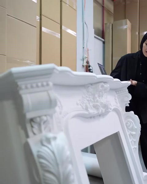 Beyaz şöminenin kıvrımlı kabartmaları ve çerçeve detayları yakından görülüyor