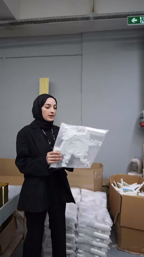 Beyaz köşe süslemesinin kabartmalı kıvrımları sunucunun ellerinde gösteriliyor.
