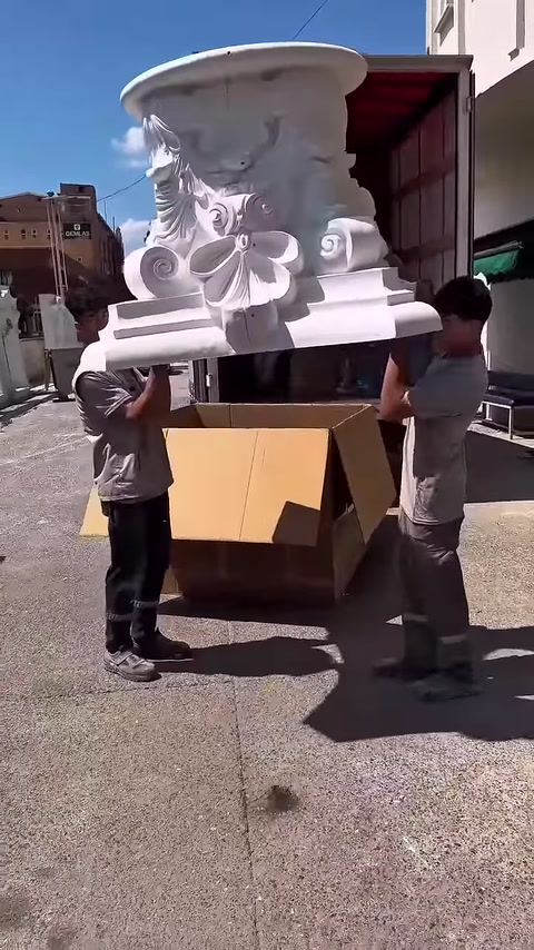 İki çalışan büyük dekoratif sütun başlığını havada birlikte tutuyor