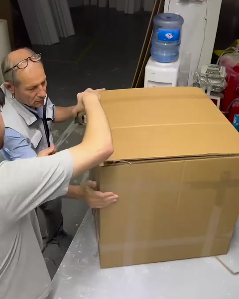 Hazırlanan büyük karton kutunun kapakları birlikte kapatılıyor