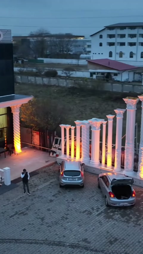 İnce ve kalın dekoratif kolonlar, avlu kenarında dönüşümlü yerleştirilmiş görünüyor