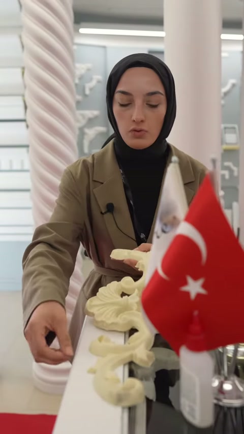 Sunucu kıvrımlı dekoratif parçayı masadan alarak incelemeye hazırlanıyor