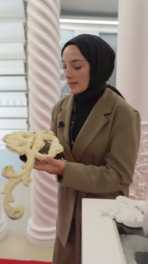 Sunucu büyük kıvrımlı motif parçasını göğüs hizasında taşıyor