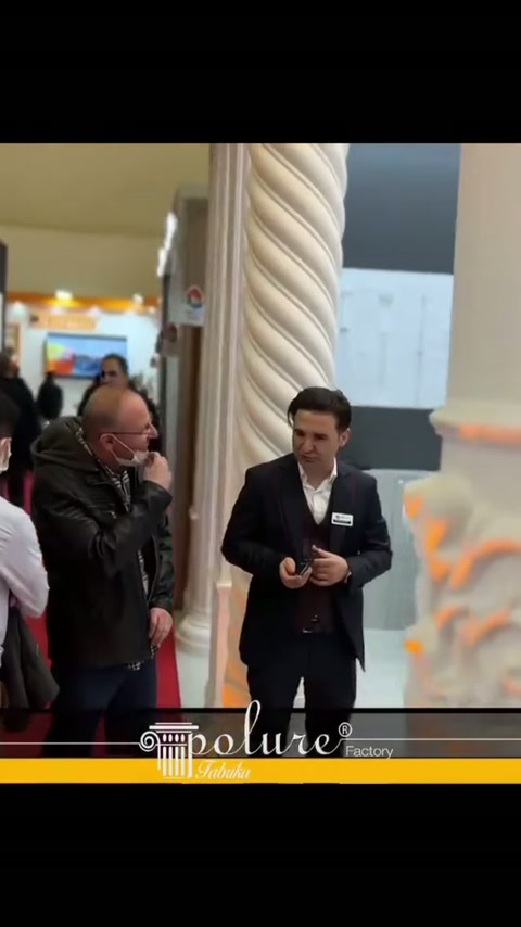 Burgulu sütun yanında stand görevlileri ziyaretçileri karşılıyor