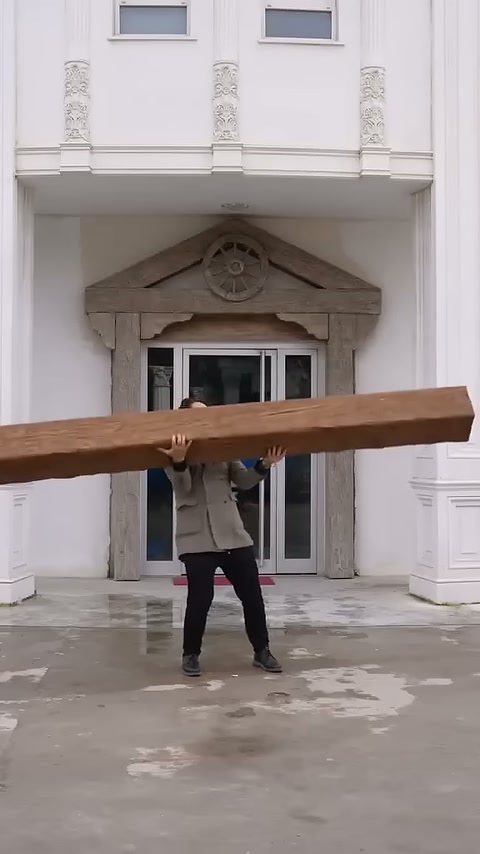 Ahşap görünümlü uzun kiriş giriş kapısı önünde kaldırılıyor.