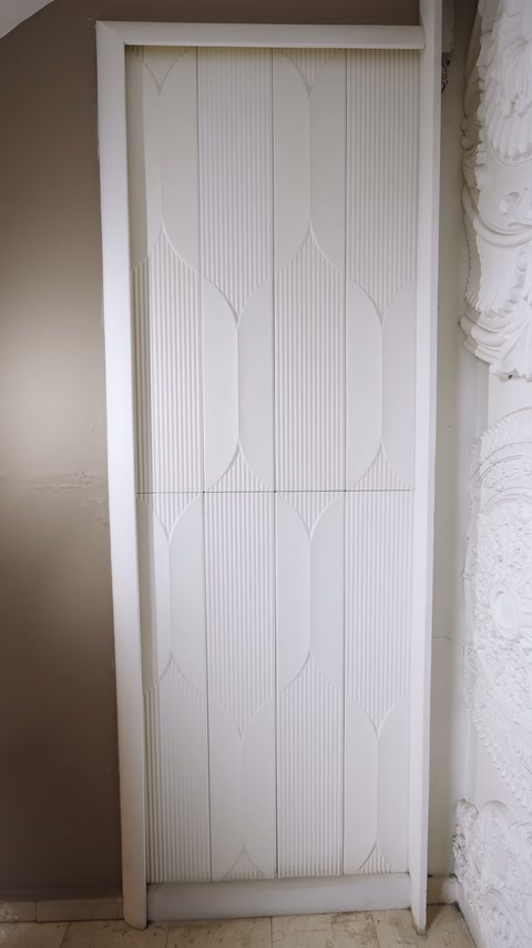 Dikey panellerle kaplanan nişte simetrik oval çizgi düzeni görülüyor