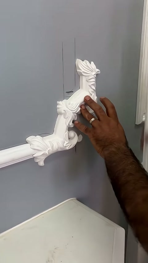 Usta dikey süsü gri duvara bastırarak konumunu ayarlıyor