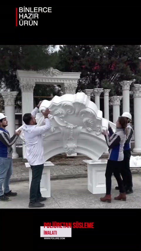 Çalışanlar kabartmalı geniş alınlık parçasını açık alanda birlikte taşıyor