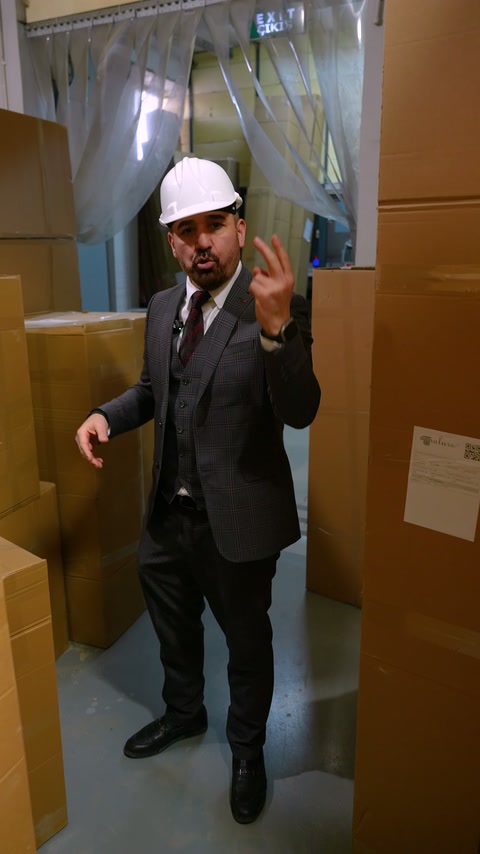 Baretli görevli sevkiyat alanındaki paketleri eliyle işaret ediyor.