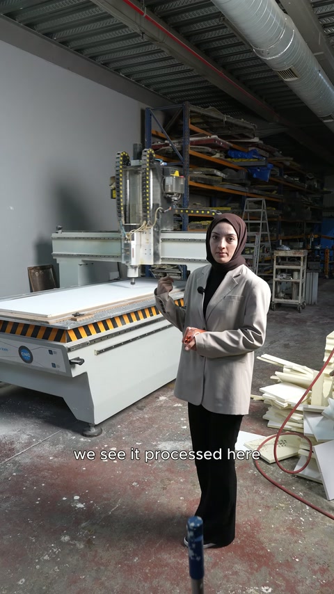 Makinenin uzun tablası, kesici başlıkları ve çalışan birlikte görülüyor