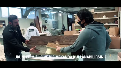 Üretim masasındaki çalışanlar uzun dekoratif parçayı birlikte inceliyor.