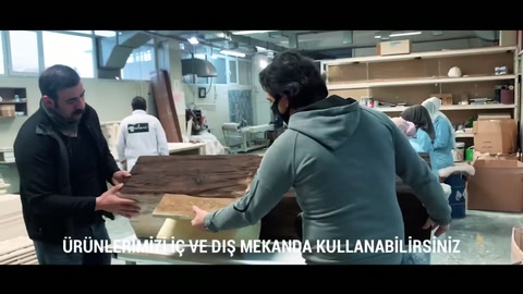 Atölyede iki çalışan açık renkli kiriş parçasını kontrol ediyor.