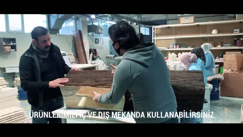 Çalışanlar üretim tezgâhında uzanan dekoratif eleman üzerinde işlem yapıyor.
